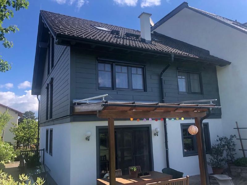Einfamilienhaus in Wien mit dunkelgrauer Siding-Fassade im Obergeschoß