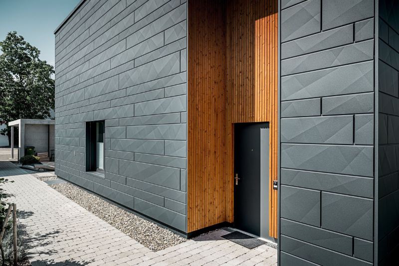 Modernes Haus mit dunkler Metallfassade und Holzelementen